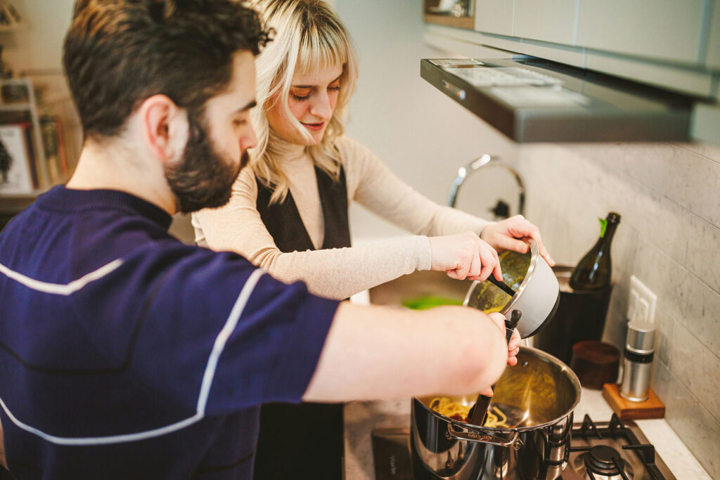 Engaged couple cooking together in their kitchen, cozy and in love, in Prospect Heights, Brooklyn.
